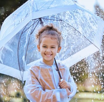 Always determined to have fun. a little girl playfully standing in the rain holding her umbrella.
