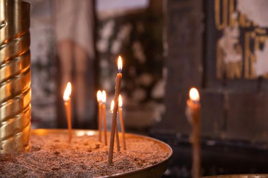 wax candles lit against the background of a cross, the concept of christian religion, prayers for the salvation of the soul, soft focus.Orthodox church, many burning candles in temple