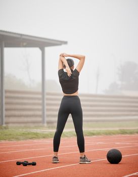 Her track record is an inspiration for other athletes. an athletic young woman stretching while out on the track.
