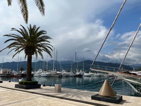 Yachts are moored at the pier against the backdrop of the mountains. Porto, Montenegro