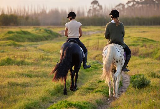 A great horse will change your life. two unrecognizable women riding their horses outside on a field.