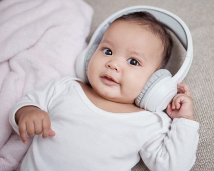 Music makes a big difference to the baby brain. High angle shot of an adorable baby wearing headphones at home.