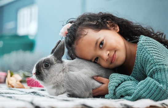 My pet rabbit loves hugs. an adorable little girl bonding with her pet rabbit at home.