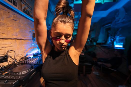 Beautiful female DJ dancing to techno in a small club