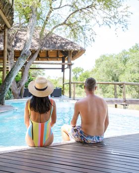 couple men and women on safari in South Africa relaxing by the pool of a luxury safari lodge ,
