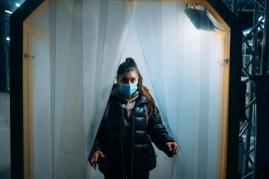 Woman at medic mask is staying in a disinfection tunnel