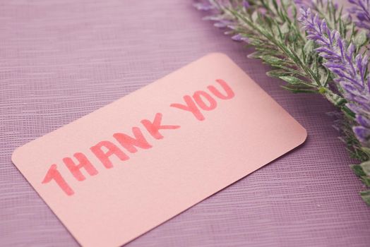 thank you message on sticky note and flower on purple background