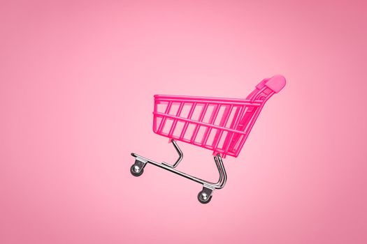 Pink shopping trolley supermarket concept. Empty trolley cart isolated pink background. Sale cart shop online marketplace. Toy pink concept sales online shopping cart supermarket sales shopping symbol