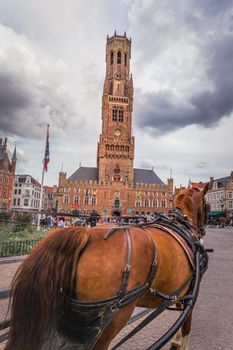 Bruges market square with Belfry tower and horse carriage, Belgium