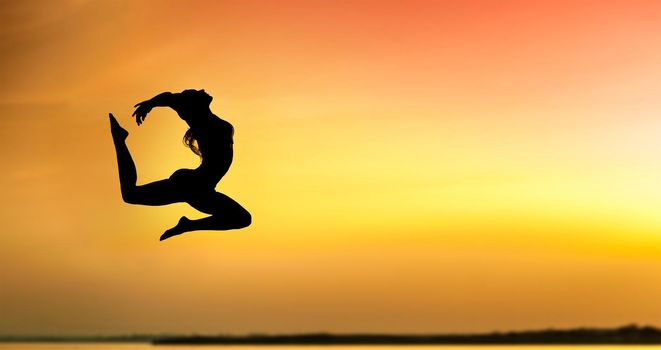 Silhouette of a young woman jumping at the sunset