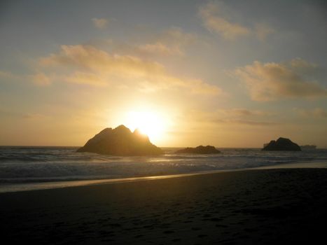 Sunset over Seal rock and Pacific ocean with large cargo ship in the background on Ocean Beach
