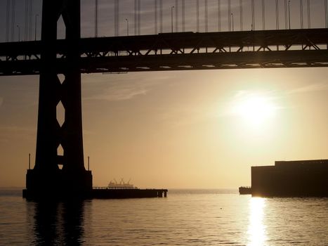 Sunrise over San Francisco Bay and through the Bay Bridge with boats in the water