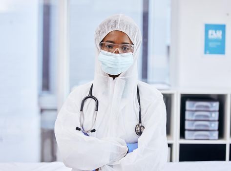 Its time to tackle covid. Cropped portrait of a confident female doctor standing with her arms folded while dressed in PPE overalls in the office.