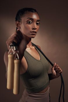 This body is a result of persistence. an attractive young woman standing alone in the studio and posing with a skipping rope before working out.