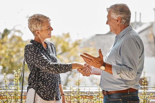 Welcome to your new home. a senior realtor shaking hands with a client.