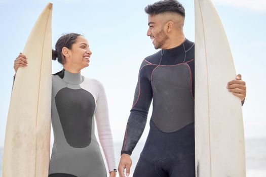 We live for these summer days. a young couple holding surfboards at the beach.