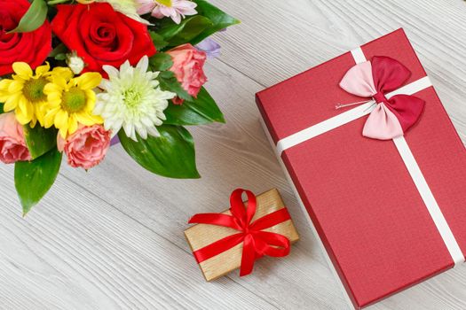 Bouquet of flowers and gift boxes on wooden boards.