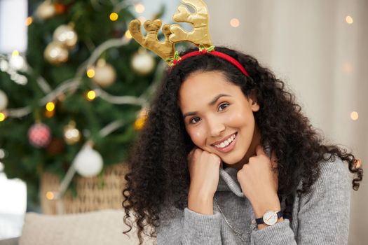 Its beginning to look and feel a lot like Christmas. Portrait of a beautiful young woman wearing a Christmas headband at home.