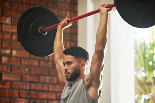 Get high on health. a young man working out with a barbell in a gym.