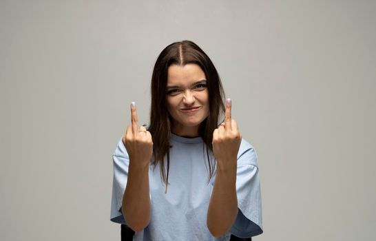 Portrait of rude vulgar woman showing middle fingers, impolite gesture of disrespect, looking with aggression hate on white background.