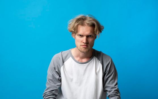 Portrait of an upset unsatisfied man standing with arms and a backs and looking in the camera isolated over white background. Negative human emotions facial expression feelings attitude.