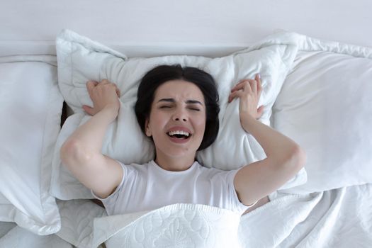 Top view, depressed woman lying in bed crying and screaming with sadness