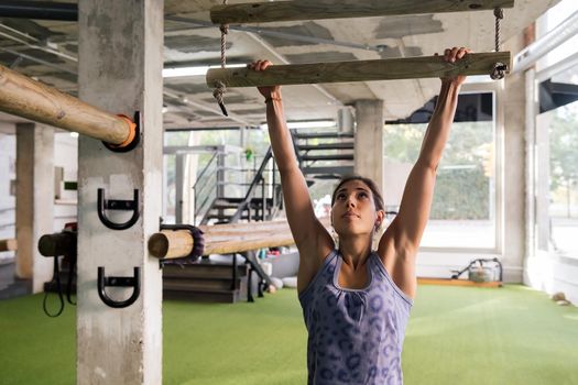 sportswoman strength training doing pullups at gym
