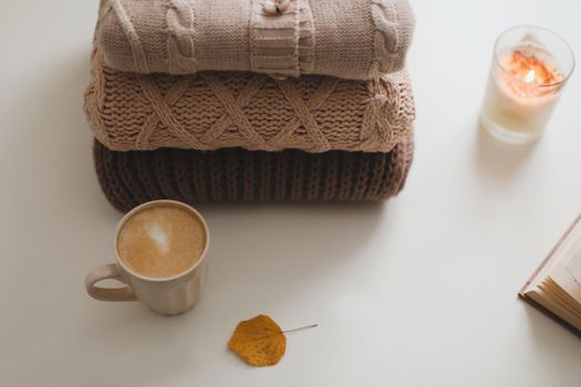 cozy comfortable hygge home atmosphere and still life with a cup, candle and sweaters