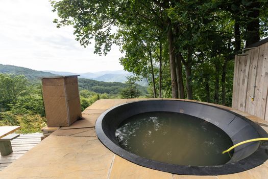 Wooden hot vat on terrace at mountains. vacation concept with hot bath outside. summer