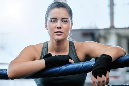 Confident, active and toned female fitness athlete in a boxing ring about to exercise at a gym. Portrait of a healthy, fit woman ready for a workout. Strong sports training instructor exercising