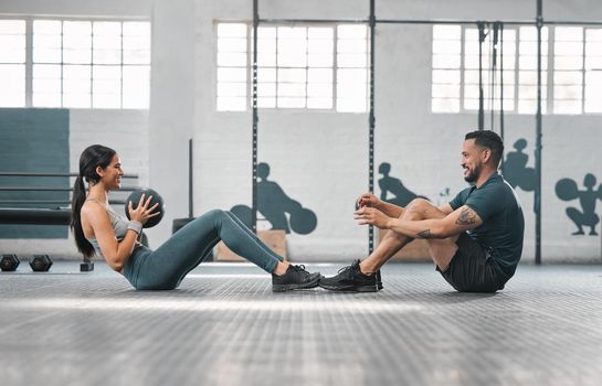 Active, sporty fitness couple or gym partners training together, doing core exercises with heavy equipment. Male trainer and female athlete having a fun workout session or class to build strength