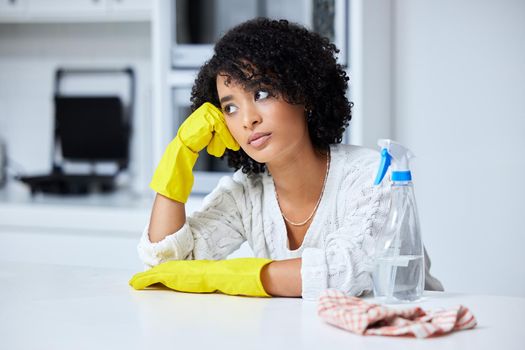 Id rather do anything else. a young woman looking unhappy while cleaning her kitchen.
