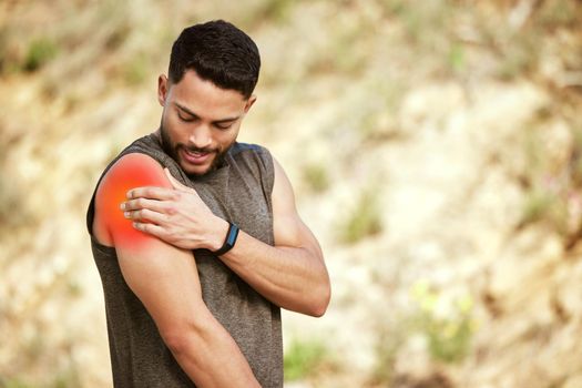 This doesnt look or feel good. a sporty young man holding his shoulder in pain while exercising outdoors.
