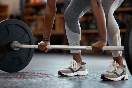 Lift with your legs. an unrecognizable and athletic young woman working out with a barbell in the gym.