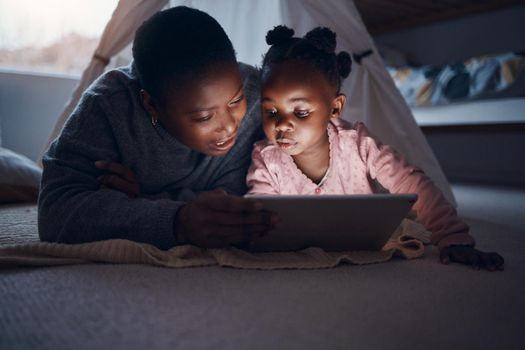 Why dont you choose a story. a mother reading bedtime stories with her daughter on a digital tablet.