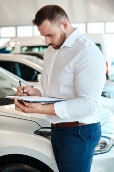 Sign on the dotted line. a car salesman writing on a clipboard.