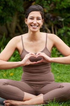 Good health is great nourishment for your body and soul. Portrait of a young woman making a heart shape with her hands while exercising outdoors.