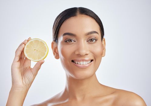 Say goodbye to blemishes with vitamin c. Studio shot of an attractive young woman holding a lemon against a grey background.