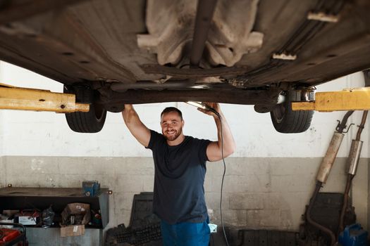 Wanting to become a mechanic is a dream theyve had since childhood. a mechanic working under a lifted car.
