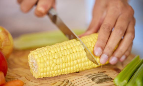 This veggie is never in short supply. a woman cutting up a stalk of corn.