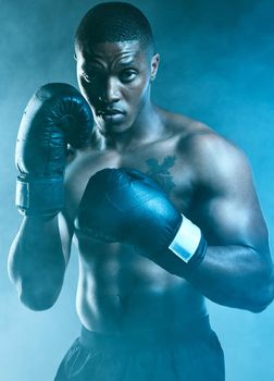 Show me what you got. Studio shot of a handsome young man boxing against a blue background.