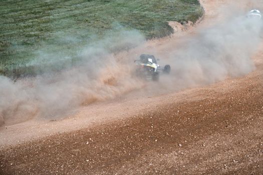 buggies on the autocross track, skidding, dust and dirt flying under the tires