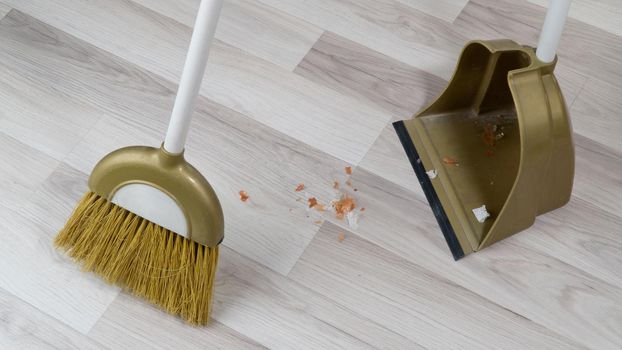 broom brush and scoop sweeping dirt off floor laminate