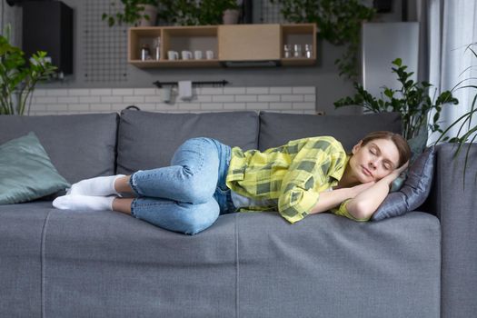 A middle-aged woman at home alone sleeps on a sofa resting from homework