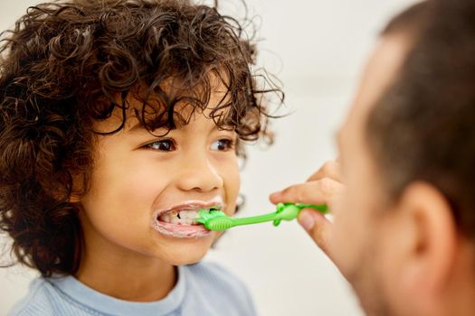 Be true to your teeth and they wont be false to you. a father teaching his son how to brush teeth at home.