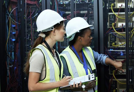 These seem nice and secure. two attractive female programmers working in a server room.