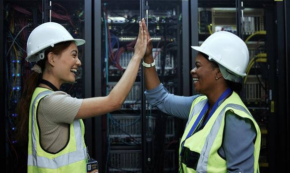 We did it. two attractive female programmers high fiving in a server room.