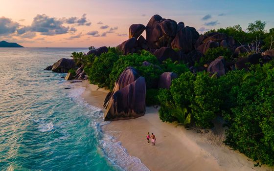 Anse Source d'Argent beach, La Digue Island, Seyshelles, Drone aerial view of La Digue Seychelles bird eye view, couple men and woman walking at the beach during sunset at a luxury vacation