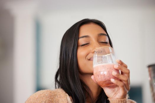 So much nutrients packed into one delicious drink. a young woman drinking a healthy smoothie at home.