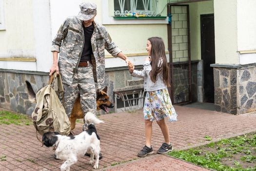 Soldier in camouflage meeting his daughter outdoors